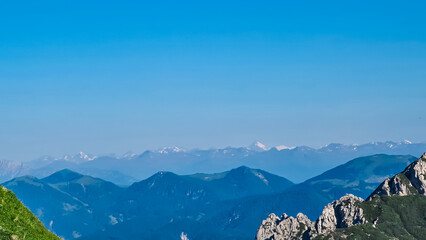 Ascending via ferrata hiking trail to mount Mangart (Mangrt), border Italy Slovenia. Scenic view of majestic mountain peaks of Julian Alps on blue sky summer day. Climb rugged extreme alpine terrain