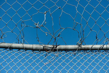 chain link fence with a few repairs on a blue sky