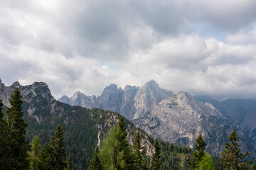 Panoramic view from Monte Lussari in Camporosso, Friuli Venezia Giulia, Italy. Looking at majestic mountain peaks of Julian Alps. Massive rock ridges of Jof Fuart, Cima di Riofreddo covered by clouds