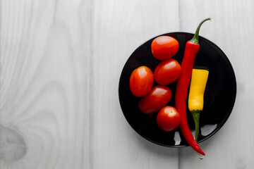 One and a half hot peppers on a black round plate.