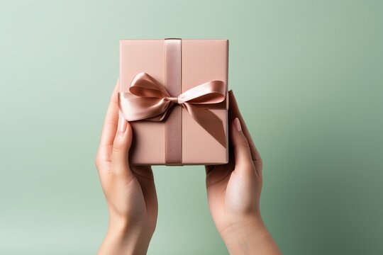 Elegant Person Holding A Perfectly Wrapped Gift On A Vibrant Solid Color Background