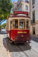 Famous and typical old red Portuguese tram, beautifully decorated, circulating on a typical cobblestone street of the Alfama neighborhood in Lisbon in Portugal.