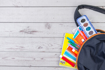 OPEN SCHOOL BACKPACK, WITH NOTEBOOKS, PENCILS, TEMPERAS AND WATERCOLORS. BACK TO SCHOOL.