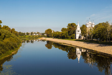 Obraz premium The Church of St. John Chrysostom on the bank of the Vologda River and its reflection in the water in the early morning. Vologda, Russia