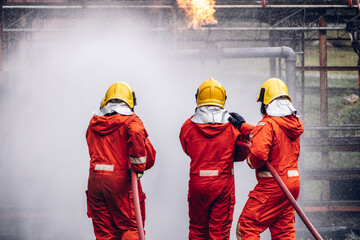 Firefighter Concept. Several firefighters go offensive for a fire attack. Fireman using water and extinguisher to fighting with fire flame.