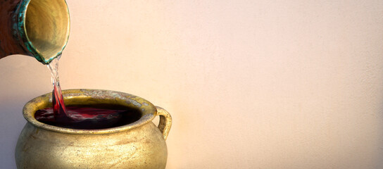 A hand holds a clay jar and pours water