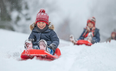 Fototapeta na wymiar Winter Wonderland: Happy Children Sledding Down Snowy Hill