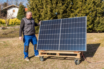 Mature man with photovoltaic solar panel in the garden.