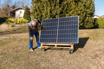 Mature man with photovoltaic solar panel in the garden.
