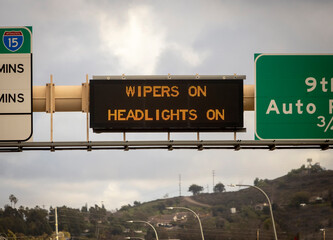 A digital sign on the 15 freeway stating Wipers On -  Headlights On to warn of a winter storm. The shot was taken in Escondido California