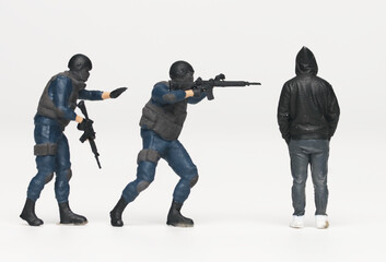 A close up miniature of anti terrorist force arresting miniature men in hood. Stop crime and violence.
