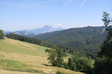 Obraz premium Blick vom Wanderweg auf dem Gahberg in Weyregg am Attersee auf ein Tal und einen Berggipfel im Hintergrund.