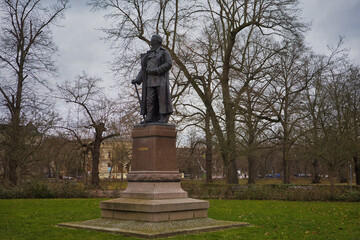 Obraz premium Ganzkörperansicht des Karl-Heine-Denkmals an der Klingerbrücke, Bronzestatue auf Steinsockel in einer Parkanlage, Leipzig, Sachsen, Deutschland