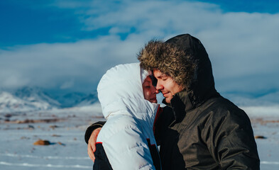 Young romantic couple embracing on mountains background in winter