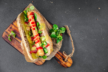 Hot Dog takeaway food sausage bun, tomato sauce, pickled cucumber, green lettuce leaf  tasty fresh eating meal food snack on the table copy space food background rustic top view