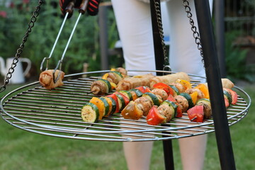 A person holding barbecue tongs and grilling vegetables, a woman or man barbecuing vegetable sticks...