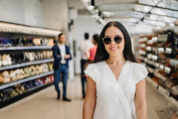  confident woman in white stands store wearing sunglasses