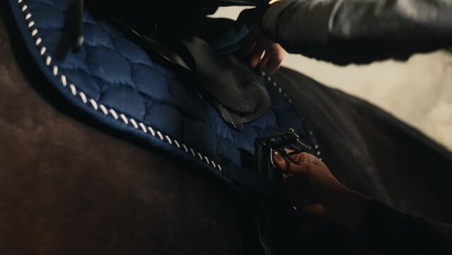 Blonde equestrian showcasing the process of putting a saddle on a horse