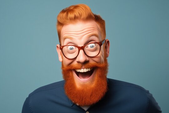 A man with a vivid red beard and stylish glasses radiates joy and personality, with a wide, infectious smile against a cool blue background