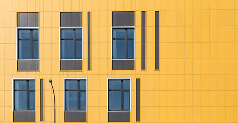 Yellow ventilated facade of a building wall with windows. fragment of an office building....