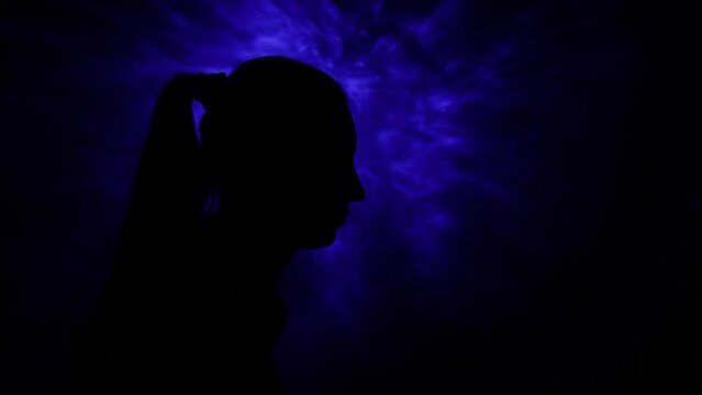 Woman thinking in the dark with closed eyes with colorful light on her face. Psychology, dreaming or meditation concept