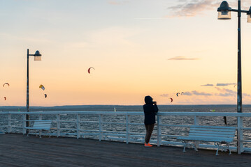 solitude lonely woman at wooden pier at autumn sea, people relax at coastal town