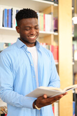 Happy student in a library, surrounded by books, smiling with a cheerful demeanor while studying.