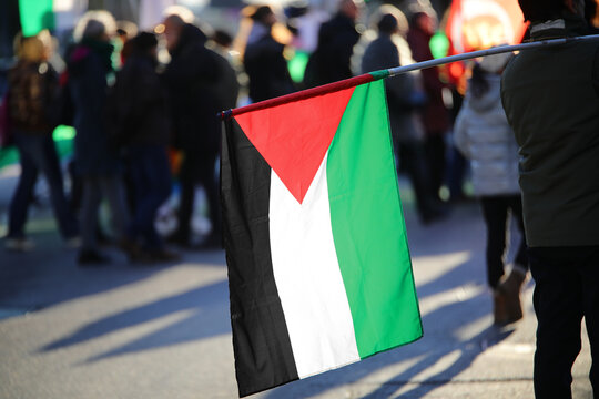 Palestine flag black white and green with red triangle waving during protest demonstration in city with many people