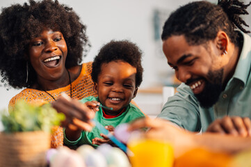 African american family painting easter eggs together at kitchen table