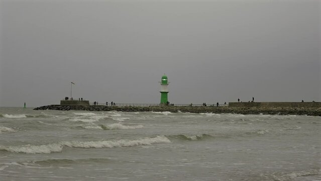 Entrance to harbor of Rostock on baltic sea. Lighthouse Molenfeuer Westmole, Warnemunde, Rostock, Mecklenburg-Vorpommern, Germany. Gruner Leuchtturm Warnemunde in Rostock Deutschland. 