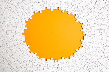 Plain white jigsaw puzzle  on yellow color background, oval shaped frame, abstract backdrop