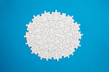 Plain white jigsaw puzzle  on blue color background, oval shaped frame