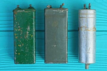 three large powerful different  dirty  square old iron electrolytic rusty capacitors  on a green...