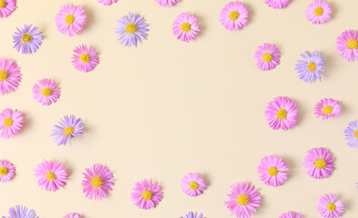 Floral stylish border frame of pink and purple flower aster on beige background. Spring and summer colorful flowers pattern. Flat lay, top view, mockup, copy space for text.