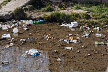 A riverbank cluttered with various plastic waste, highlighting pollution.