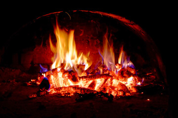 Wood logs are engulfed in flames, radiating heat and light.