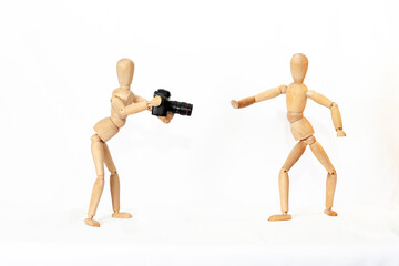 Wooden figure of a mannequin with a camera on a white isolated background...
