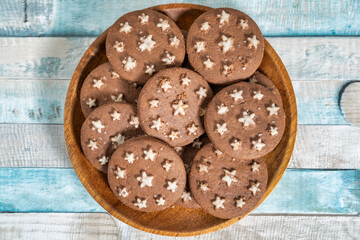 Delicious sweet cocoa cookies biscuits on a wooden plate . Overhead shot. Colorful blue background.