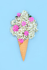Surreal hawthorn blossom and rose campion flower ice cream cone concept. Fun edible food art spring composition for logo, gift tag, birthday, mothers day, holiday vacation on blue.