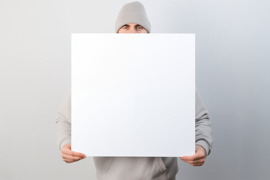 Mann hält weißes Schild mit Textfreiraum, Junger smarter Mann mit einem weißen leeren Schild für Werbung und Botschaften