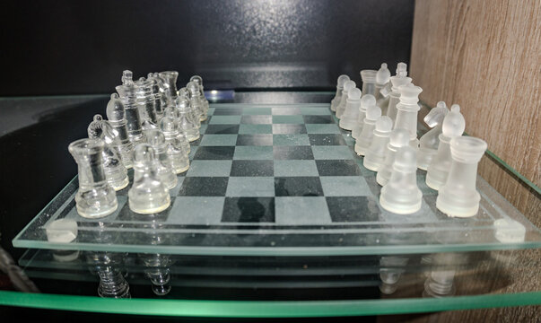 Crystal glass chess pieces on a glossy chessboard. Strategy concept.