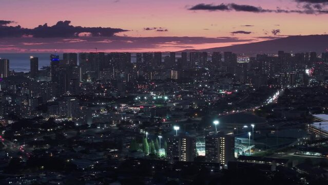 Modern cityscape of Oahu island in Pacific. Downtown Honolulu sunset views. Cinematic aerial above Honolulu capital of Hawaii state, USA. Scenic pink purple sunset sky above city illuminated at night