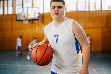 A junior basketball player dribbling a ball on training at indoor court.