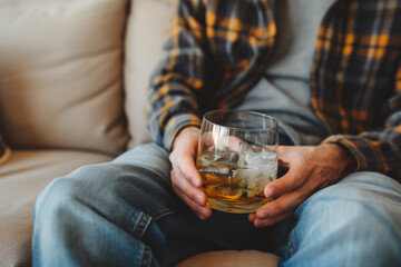 Alcoholic sitting on the sofa with a glass of alcohol, alcoholism concept. Background with selective focus - obrazy, fototapety, plakaty