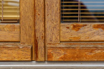 weathered wooden door, maintenance needed, peeled varnish caused by sunny and rainy weather.
