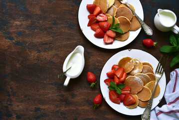 Delicious tiny pancakes with fresh strawberry for a breakfast. Top view with copy space.