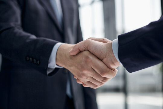 executives shaking hands in front of their manager and a colleague