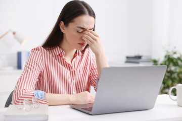 Woman suffering from headache at workplace in office