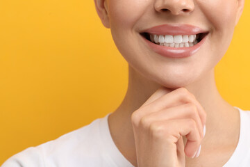 Woman with clean teeth smiling on yellow background, closeup. Space for text