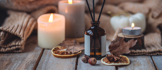 Obraz na płótnie Canvas Concept of cozy fall home atmosphere, aromatherapy. Perfume, apartment aroma diffuser with autumn scent of pumpkin spicy sweet pie, cinnamon, anise. Room decor: pumpkins, dry orange, wool plaid banner